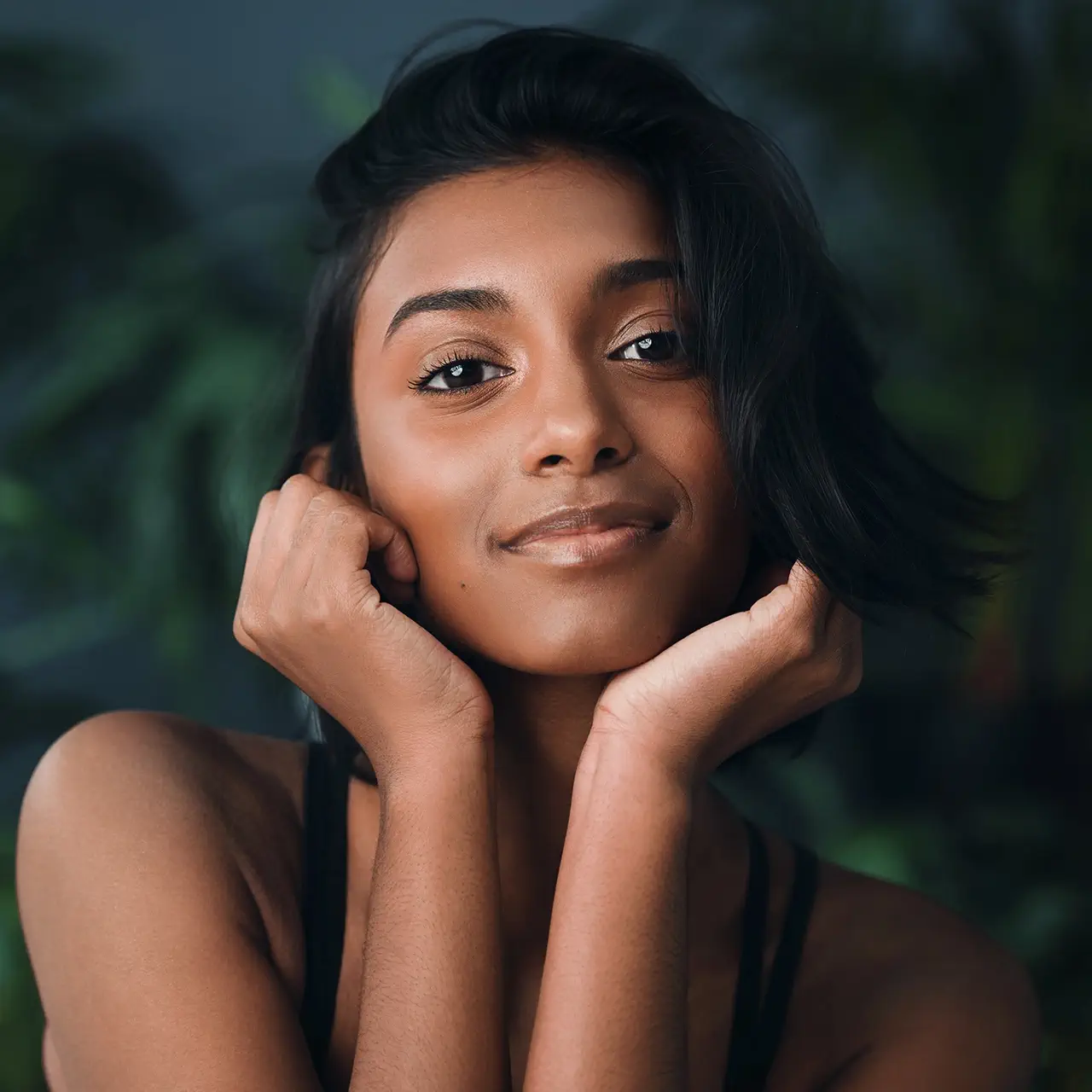 Woman resting her hand near her jaw and looking toward the camera.